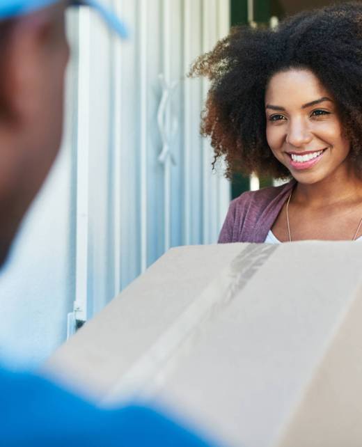 Shot of a postal worker delivering a package to a young female customer.